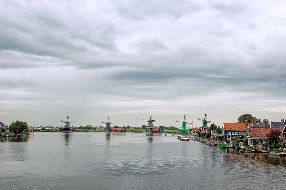 De rij molens van de Zaanse Schans langs de Zaan onder een bewolkte hemel