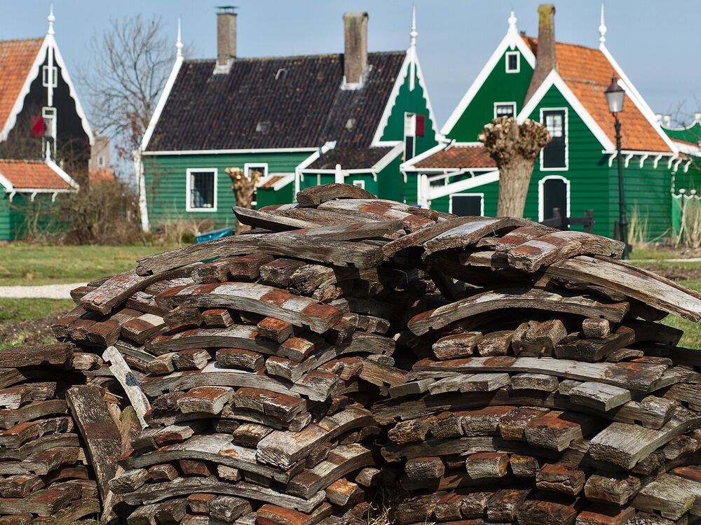Een stapel houten duigen voor de groene houten huizen van de Zaanse Schans